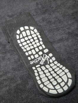 A black grip sock with white non-slip patterns and active text in the best logo format.