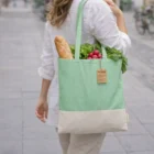 Woman carries a green Recycled Cotton Skadi Eco Bag filled with bread and vegetables.