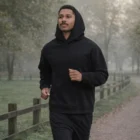 Man jogging in the park, wearing a black Box Minus Hood [-4Cm] hoodie and black pants.