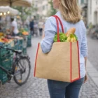 Woman with a Pacifico Large Jute Totes 28L bag filled with lettuce, bananas, and bread.