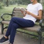 Woman wearing Victory Women's Pants sits on a park bench reading a book.