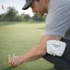 Man places Long Tees Caddies pouch labeled YOUR LOGO HERE on his belt while on grass.