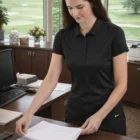 Woman in Nike Ladies Dri-FIT Icon Piqué Polo organizing papers at an office desk with windows.