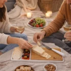 Two people use Bamboo Plates for wine, cheese, and snacks during a candlelit picnic.
