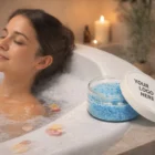 Woman relaxing in a bubble bath with 100G Bath Salts Jar Gifts, surrounded by candles.