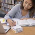 Woman studying with books, laptop, and a 7X7X4Cm Adhesive Cube With Side Print.