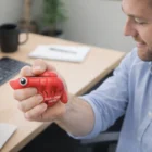 Man squeezes Stress Balls at desk with laptop, notebook, and more stress balls.