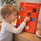 Child opens door on a Chocolate Advent Calendars near Christmas tree.