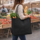 Woman holding a Darani Page Recycled Tote Bag with vegetables and bread at an outdoor market.