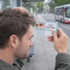 Man using Travel Comb W/ Mirrors at bus stop, reflection and Your Logo Here visible.