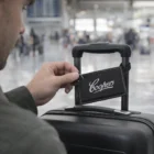 Man with suitcase and Friesland Luggage Tags at airport terminal.