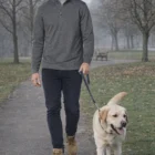 Man in a Kem Men's Half Zip L/S Sweat Top walks a yellow Labrador on a park path.