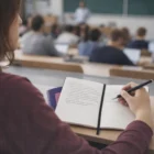 Student taking notes in an Ileather Notebook A6 during a classroom lecture.
