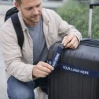 Man securing suitcase outdoors with Quick Branded Premium Luggage Straps displaying your logo.
