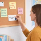 Woman pinning an Adhesive Note Pads 75Mm X 127Mm (1 Colour Print) to a corkboard in the office.