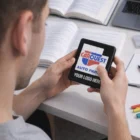 Person holding phone with Carquest Auto Parts logo and Tile Slide Puzzle Games on desk.