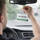 Man hangs Air Freshners with 'Your Logo Here, Auto Service Centres' on car's rearview mirror.