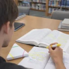 Using Triangle Customised Highlighters to mark notes at a library table with open books.