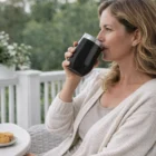 Woman outside sipping from 320Ml Modern Reusable Vacuum Cup, cookies on a nearby plate.