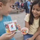 Kids share Candy - 50 Gram Jelly Beans outdoors, smiling together on a bench.