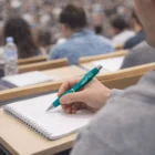Student taking notes with Viva Brandable Ball Pens during a crowded classroom lecture.