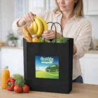 Woman places bananas into an Express Paper Kraft Bag Large filled with fresh produce and juice.
