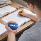 A student studies with books and squeezes a Stress Balls Footie labeled ICON logistics.