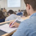 Student takes notes with Vale Falcon Pens in a lecture hall, whiteboard in front.