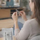 Woman files nails with Basic Manicure Set Custom Items while relaxing and watching TV.