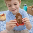 Smiling boy holds a Moulded Chocolate Frogs at a picnic.