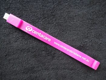 Pink Centacare plastic USB cable with website, shown on a black textured surface.
