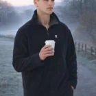 Man in Mens Polar Fleece Contrast Branded Jacket holds coffee on frosty path.