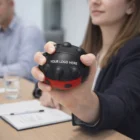 Woman holding a Lady Bug Stress Ball featuring your logo at a meeting table.