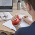 Person studying with notebook, squeezing a Footy Stress Ball in one hand.