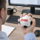 Person squeezing a Stress Ball Soccer at a desk for stress relief.