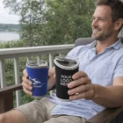 Smiling man on porch holds two Schooner Holders; one displays "YOUR LOGO HERE.