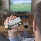 A man holds a Promo Stress Balls Truck 107mm while watching TV in the living room.