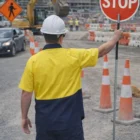 Worker in Hi-Vis Two-Tone Short Sleeve Work Shirt holding STOP sign at roadwork site.