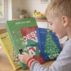 Smiling boy opens Standard Christmas Countdown Chocolates at the breakfast table.