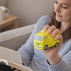 Woman holding a yellow Stress Balls - Cement Truck with Your Logo Here while reading on a sofa.