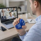 Man on video call holding Stress Ball Large Dice With White Dots with YOUR LOGO HERE printed.