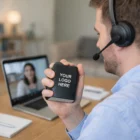 Man on video call with headset, holding Stress Shaped Black Book labeled Your Logo Here.