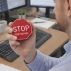 Man holding a Stress Shaped Stop Sign at a desk with monitors.