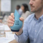 Man holding a Stress Shaped Water Drop stress ball with YOUR LOGO HERE text on it.