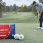 Man putting on a green with Titleist Dt Customized Golf Ball and box in the foreground.