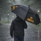 Person holding an Executive Logo Printed Golf Umbrella while walking in a rainy park.
