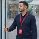 Man in navy shirt with Unprinted Lanyards and blank badge, holding a door handle.