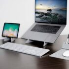 Laptop and tablet on stands with keyboard and mouse on a tidy desk.