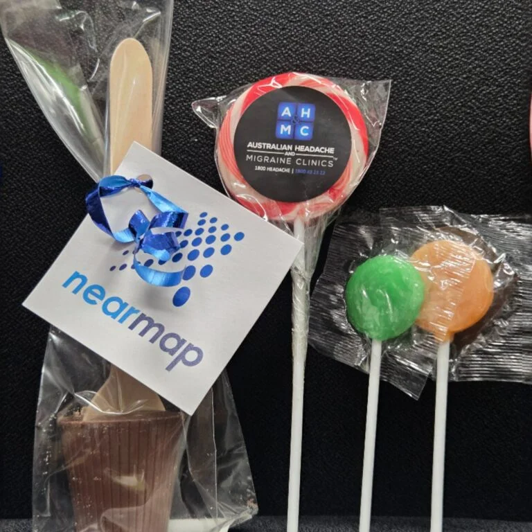 Assorted lollipops and a chocolate treat—top promotional items 2025 with Nearmap tag and ribbon.