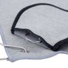 Close-up of a gray fabric mat with black trim and metal grommets on the edge.